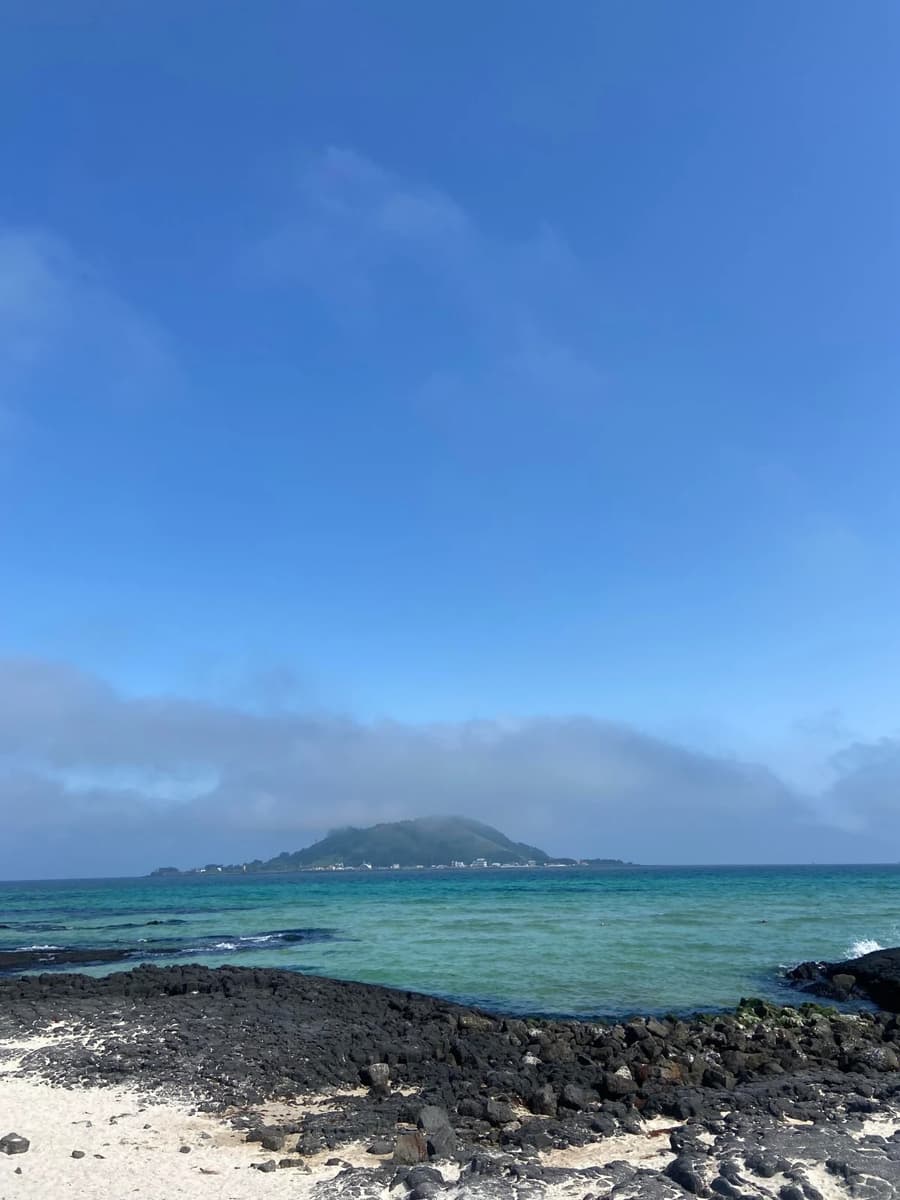 Emerald water and a basalt beach with an oreum on the horizon