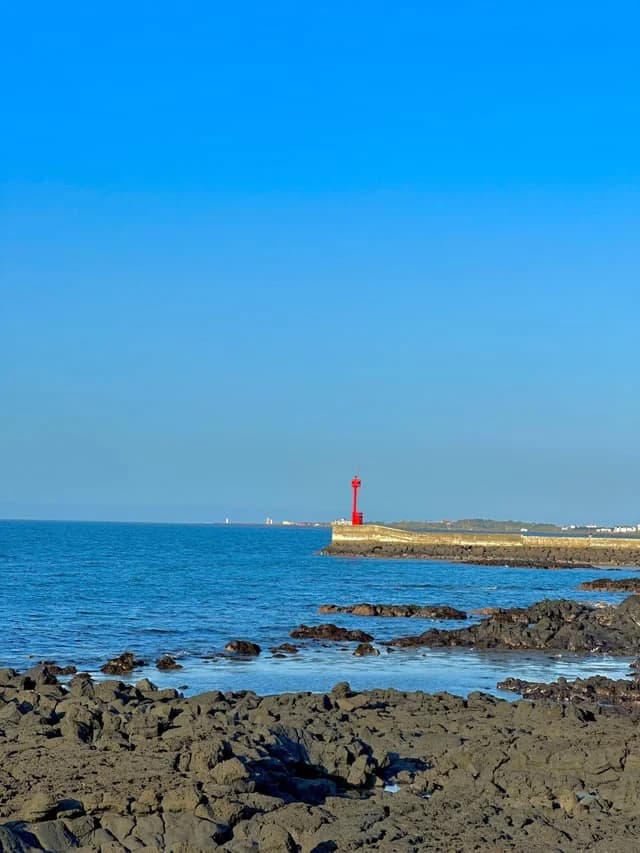 Red breakwater lighthouse over the blue sea, Jeju