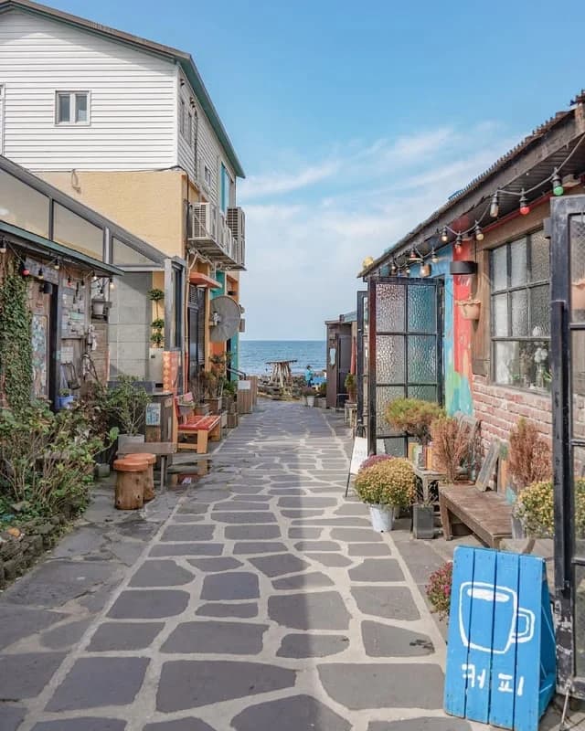 Stone café alley opening onto the sea in a Jeju seaside village