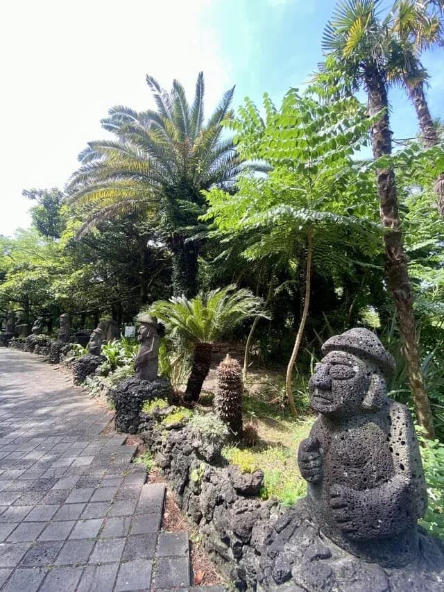 Dolharubang stone grandfathers along a fern-lined garden path