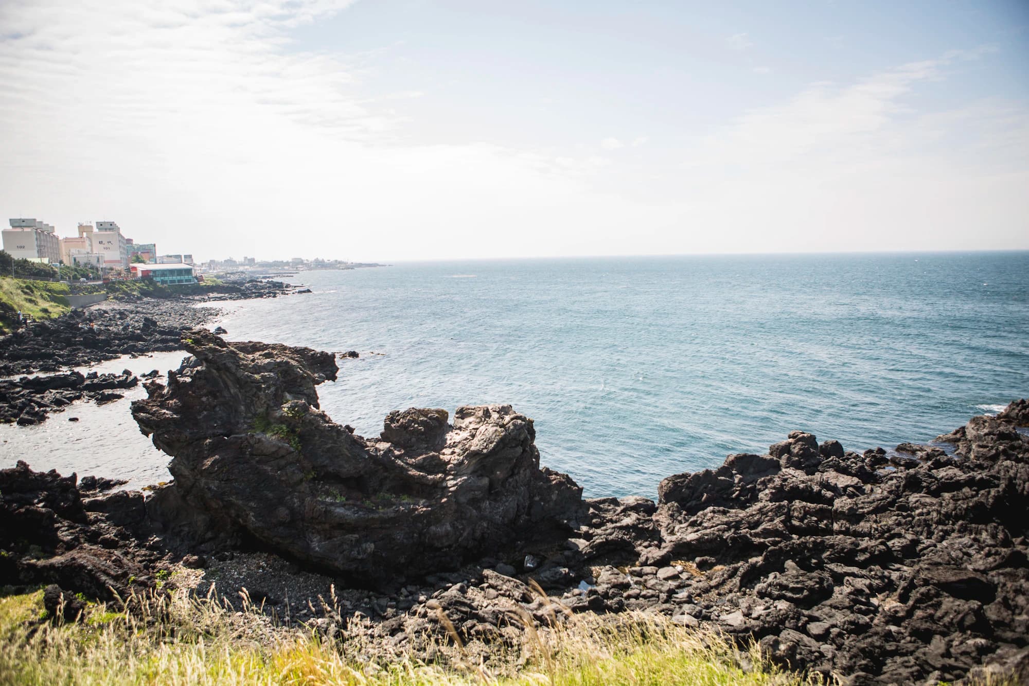 Volcanic basalt cliffs over emerald water, Jeju coast