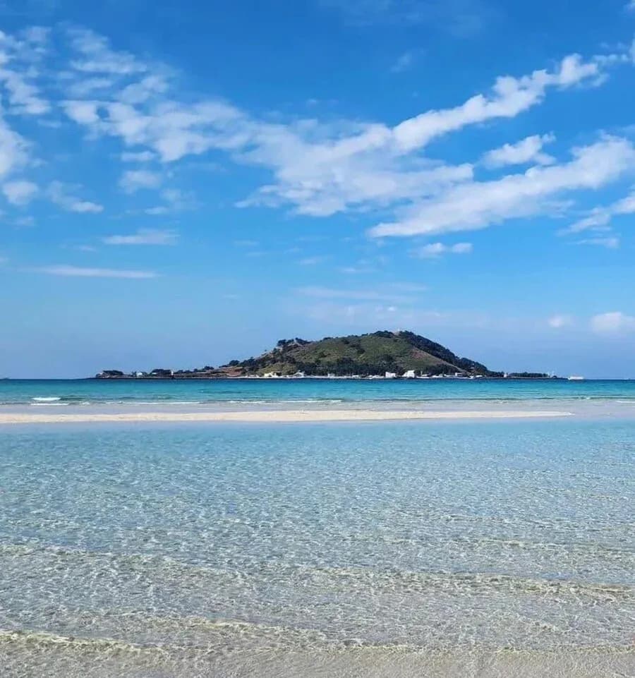 Crystal shallows of Hyeopjae beach with Biyangdo island beyond