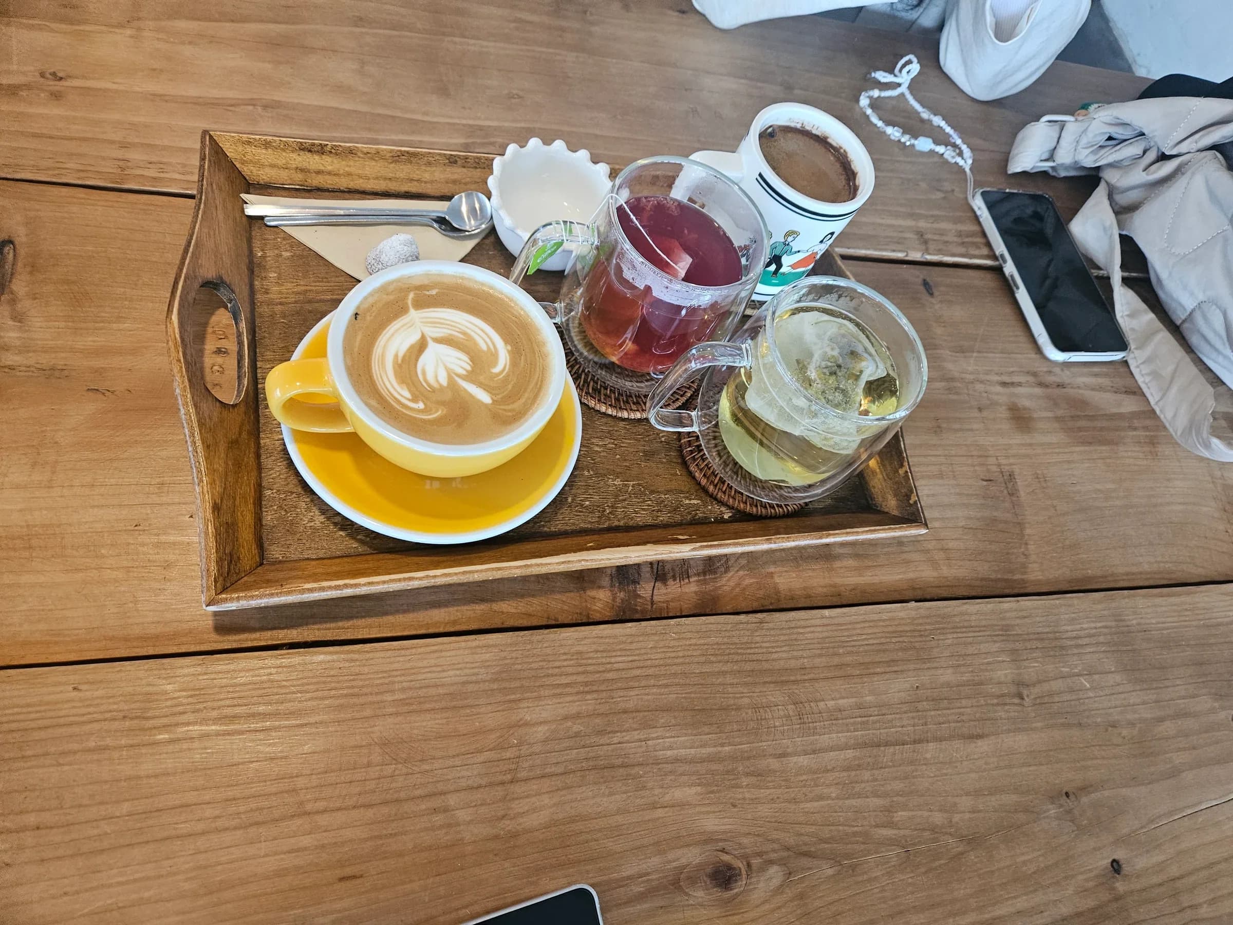 Welcome latte and tea on a wooden tray at a Jeju cafe