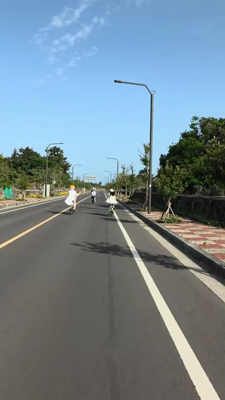 Three cyclists riding along a quiet Jeju road