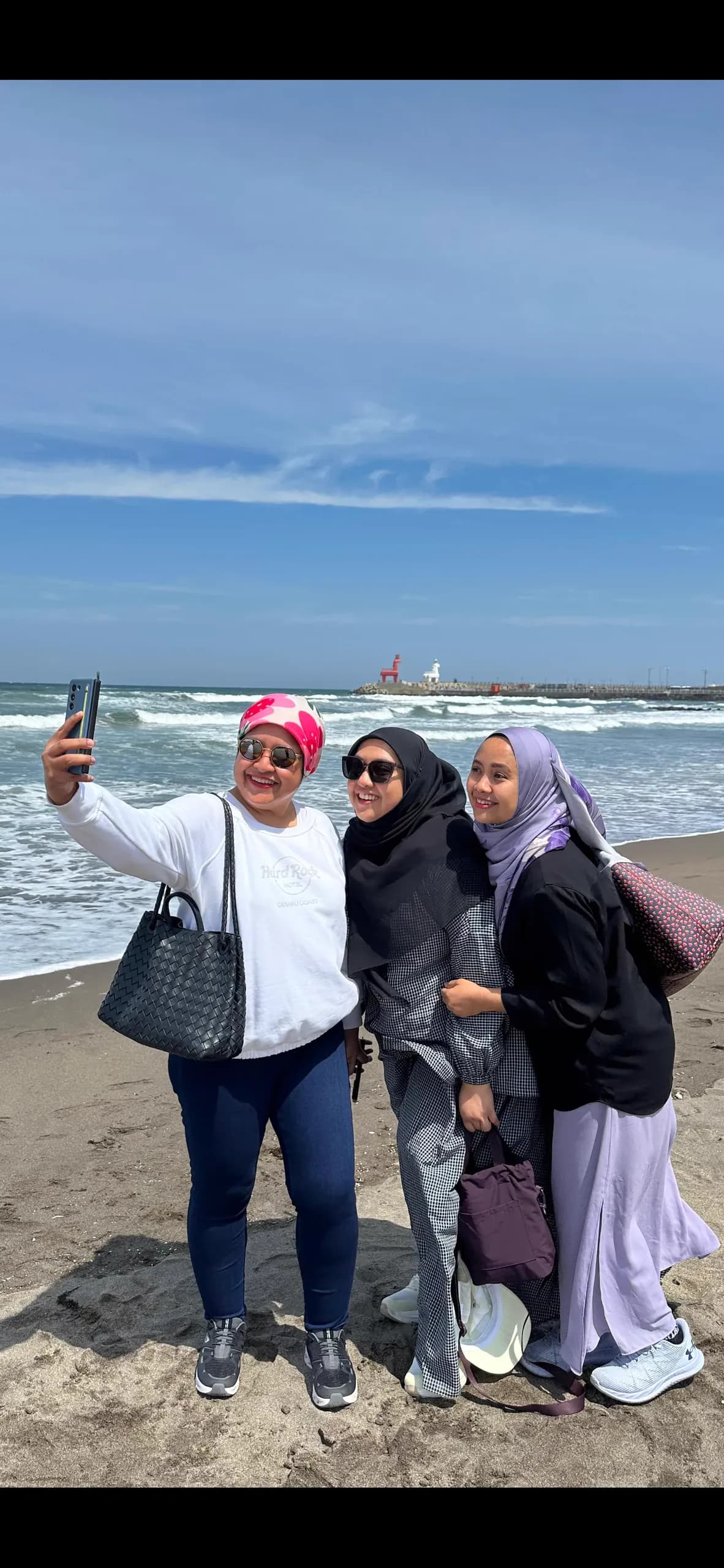 Beach selfie with a lighthouse and breakwater behind