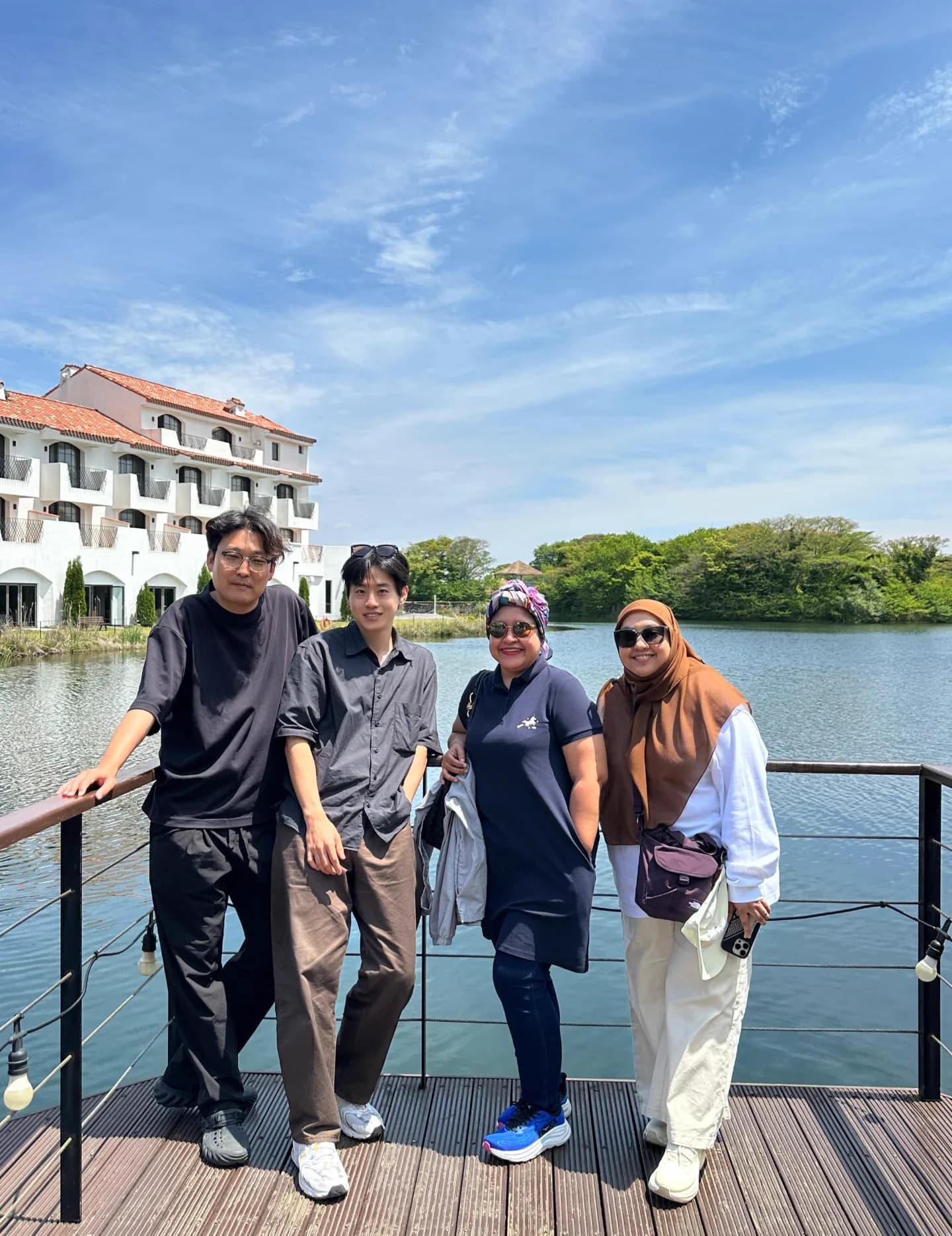 Group photo by a garden lake with a white Mediterranean-style building