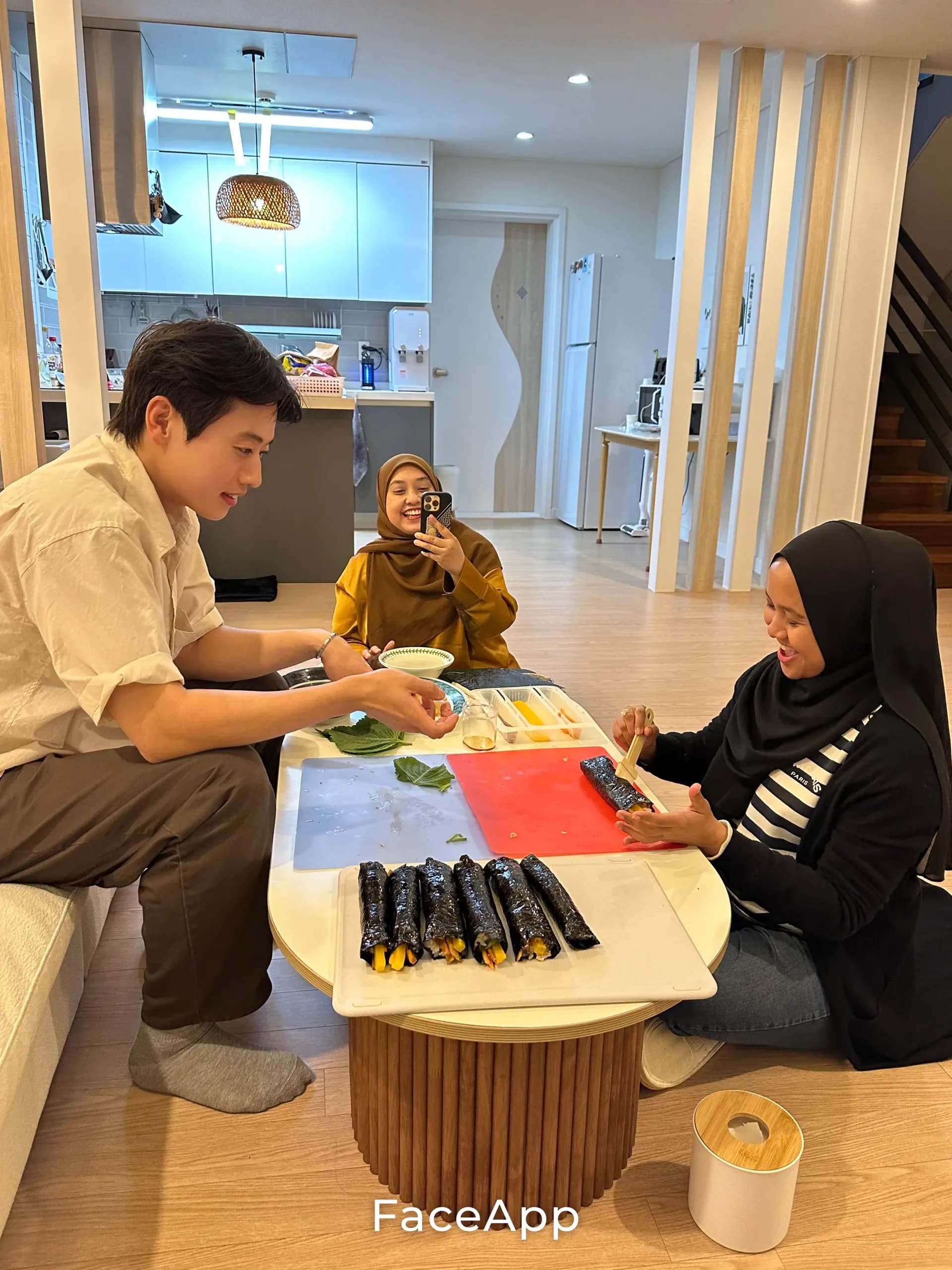 Rolling kimbap together on the villa floor — Nasir hosting two guests