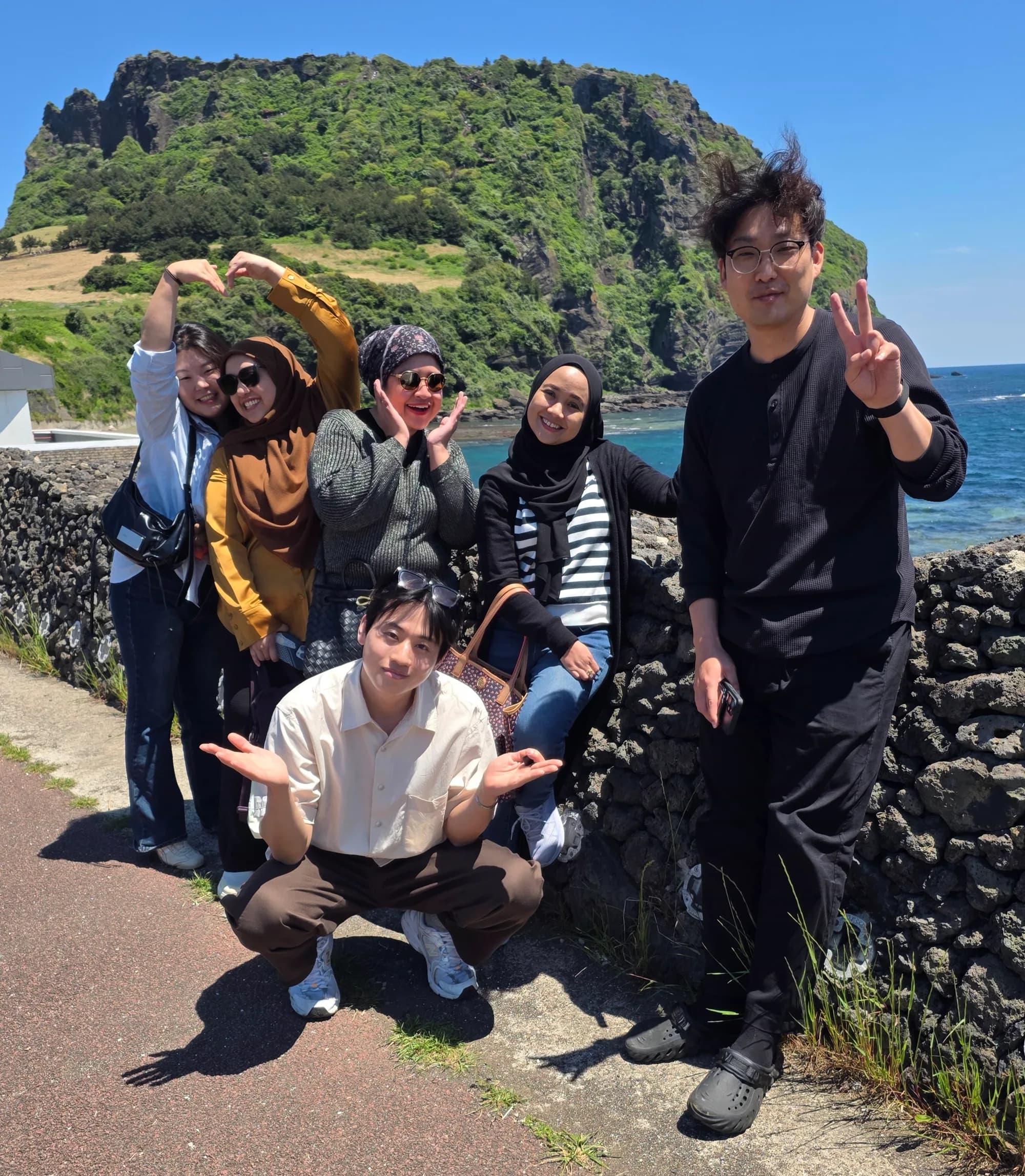 Group photo at Seongsan with peace signs and heart hands