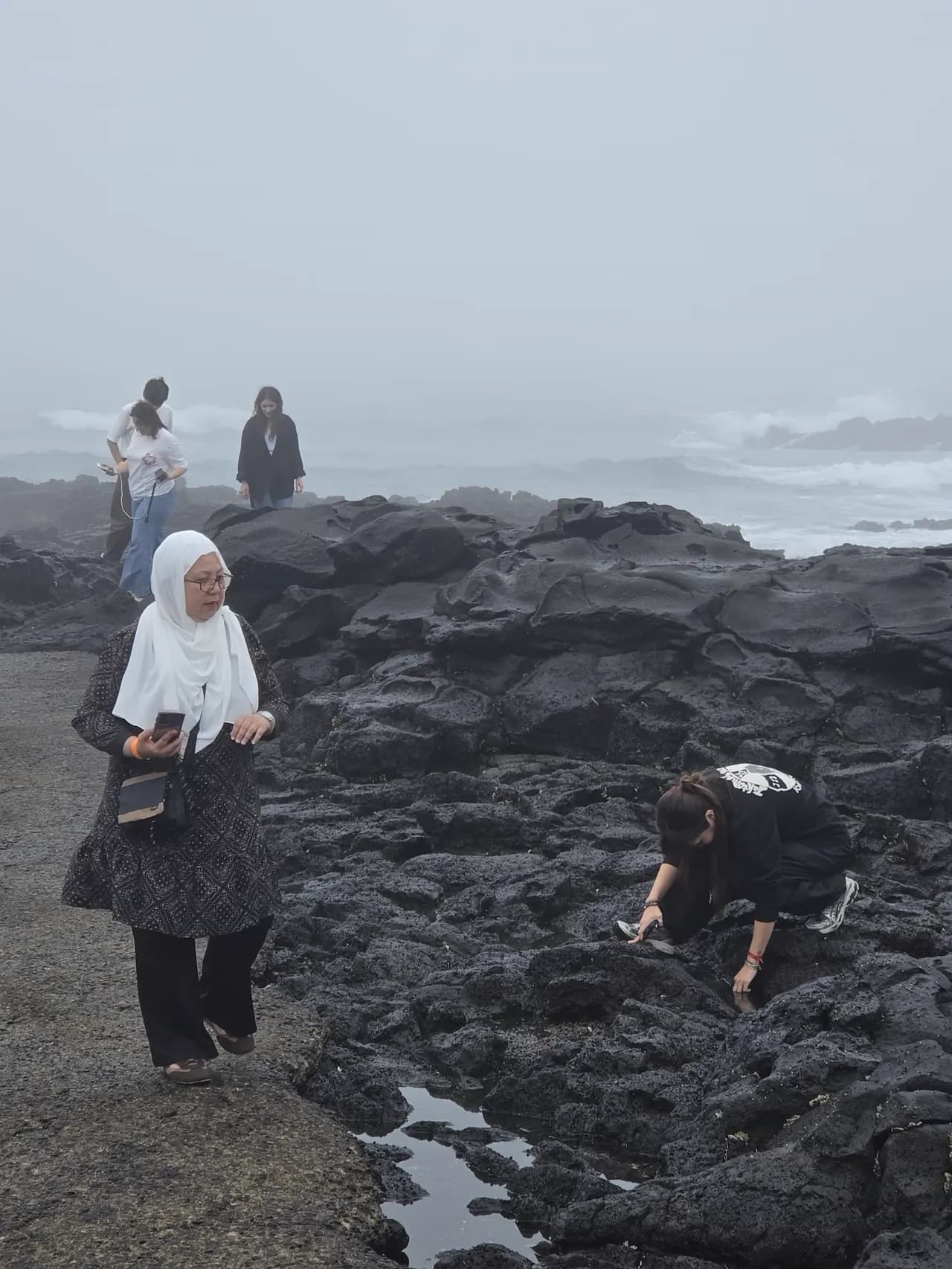 Guests on the tidal rocks as dusk settles over the sea