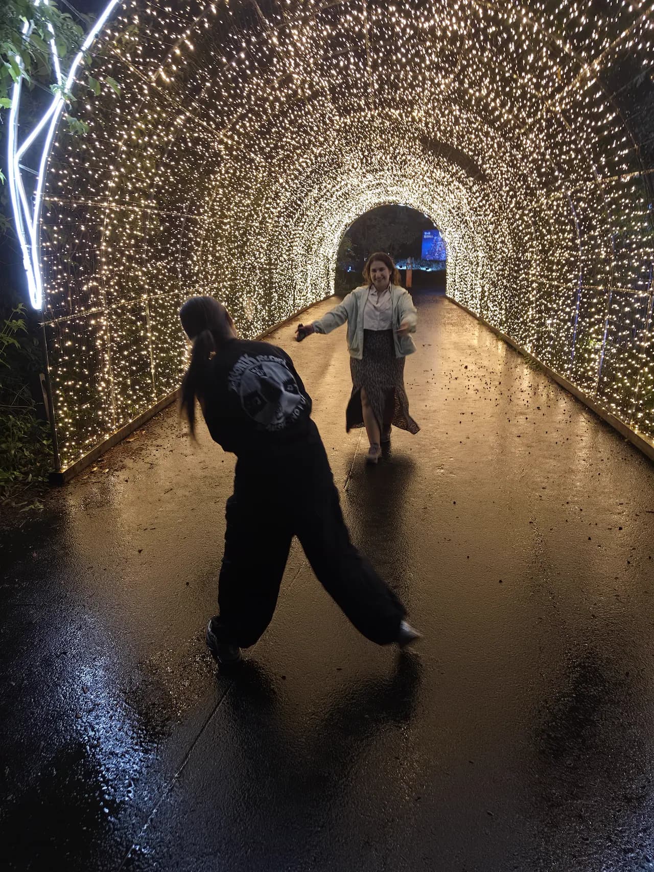 Guests in a glowing fairy-light tunnel on the Jeju City night loop