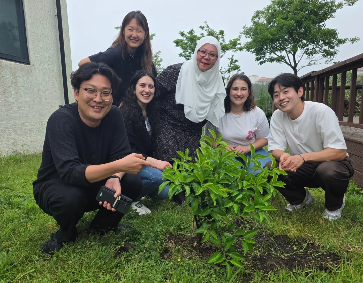 Cohort kneeling around a freshly planted Sadaqah Jariyah tangerine tree at the villa garden